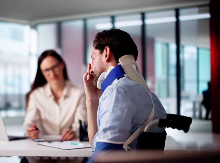 Mężczyzna w kołnierzu ortopedycznym omawia odszkodowanie za szkody osobowe z prawnikiem.