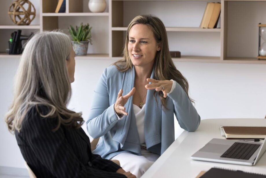 Dwie kobiety dyskutują na temat obsługi prawnej firm przy biurku z laptopem.
