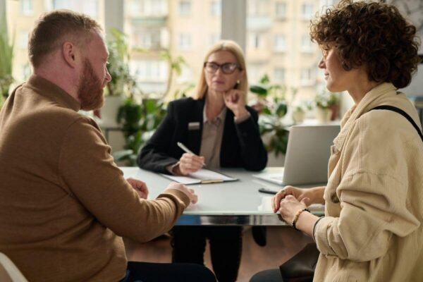 Para rozmawia przy stole, podczas gdy adwokat rozwodowy notuje szczegóły.